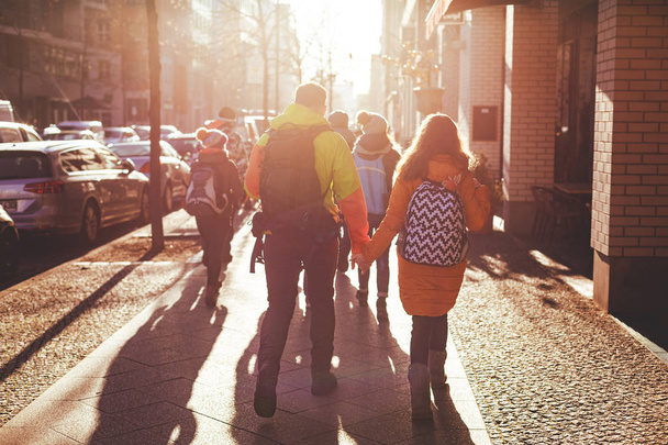 Un groupe de jeunes marchent dans les rues de Berlin en hiver. Certains couples se tiennent la main. Tourné en contre-jour avec un soleil éclatant. décembre 2018
. - Photo, image