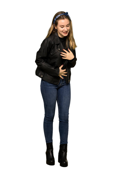 Una toma completa de una adolescente con chaqueta de cuero sonriendo mucho mientras pone las manos en el pecho sobre un fondo blanco aislado
 - Foto, Imagen