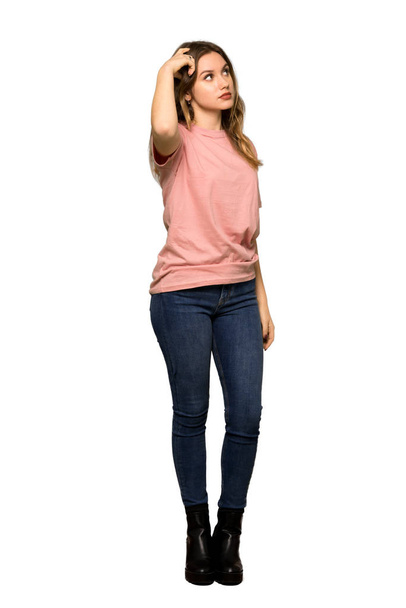 A full-length shot of a Teenager girl with pink sweater having doubts while looking up on isolated white background - 写真・画像