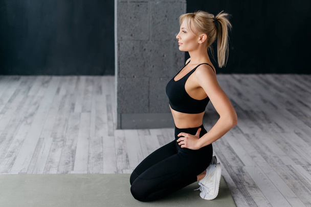 athletic woman sitting on mat in fitness studio - Foto, imagen