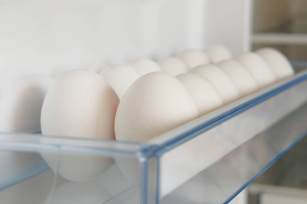 Uova di pollo crude bianche dal frigorifero. Uova su ripiano di frigorifero. Conservazione del cibo a casa
. - Foto, immagini