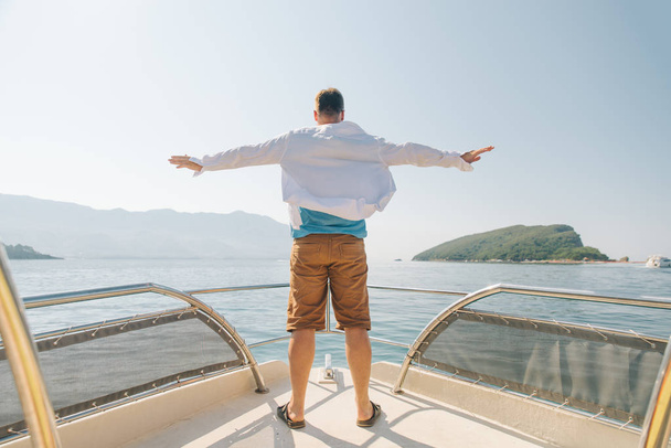 man standing with rising hand at nose of the boat. summer vacation - Photo, image