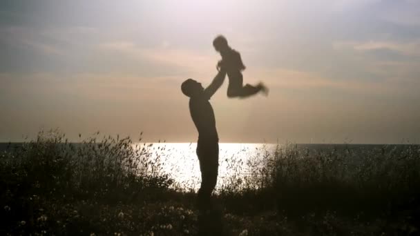 silhouette Père et fils s'amusent sur la plage au coucher du soleil, papa jetant le jeune garçon dans les airs
 - Séquence, vidéo
