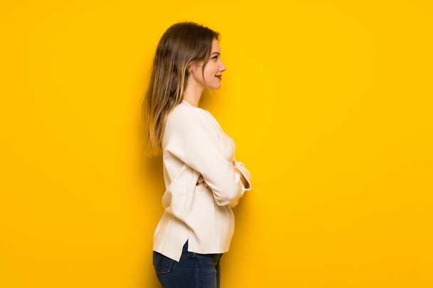 Adolescente chica sobre amarillo pared en posición lateral
 - Foto, imagen