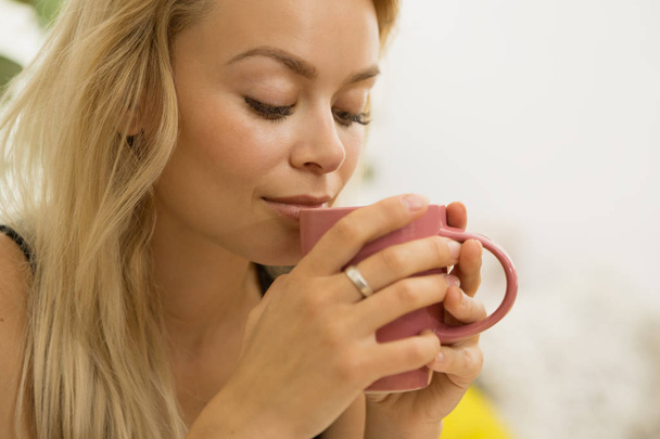 Возделывается вблизи великолепной молодой женщины наслаждаясь утренним кофе нюхает вкусный аромат свежеваренного напитка улыбаясь глазами закрытые удовлетворение наслаждение запах Арабика пить чашку
 - Фото, изображение