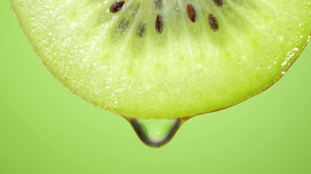Cerca o macro de una rebanada de kiwi, una gota de agua cae en cámara lenta. La fruta desprende frescura y está llena de jugo rico en vitaminas y energía. Concepto de frutas frescas, jugos y kiwi
 - Metraje, vídeo