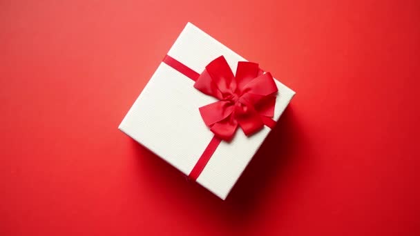 Вид сверху на подарок, завернутый в полосатую подарочную бумагу, украшенную красной лентой
 - Кадры, видео