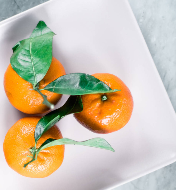 Tangerines με αφήνει στο πιάτο - εσπεριδοειδή και υγιείς διατροφικές flatlay στυλ έννοια - Φωτογραφία, εικόνα