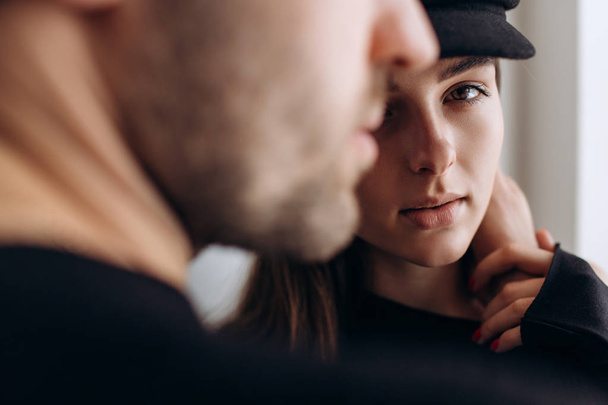 Two hipster models: a man and a woman in a blank black t-shirt, jeans and posing. in a black hat, cap, love, kisses - Fotó, kép