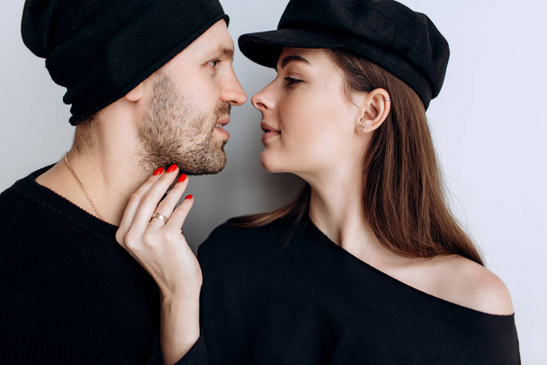 Two hipster models: a man and a woman in a blank black t-shirt, jeans and posing. in a black hat, cap, love, kisses - Фото, зображення