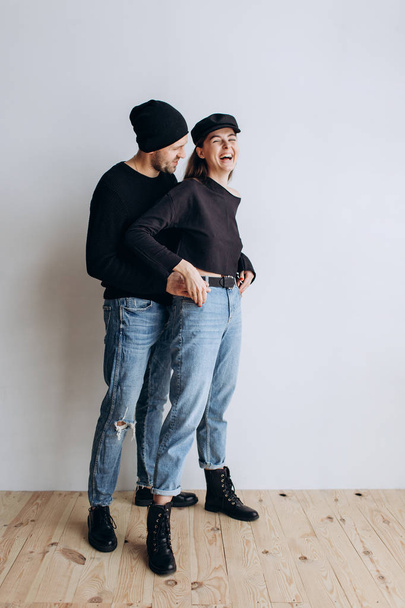 Two hipster models: a man and a woman in a blank black t-shirt, jeans and posing. in a black hat, cap, love, kisses - Photo, Image