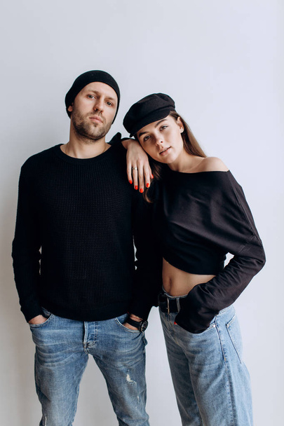 Two hipster models: a man and a woman in a blank black t-shirt, jeans and posing. in a black hat, cap, love, kisses - Foto, Bild