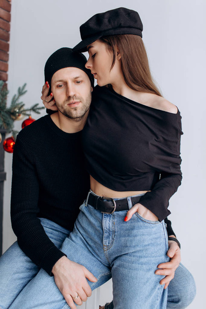 Two hipster models: a man and a woman in a blank black t-shirt, jeans and posing. in a black hat, cap, love, kisses - Foto, immagini