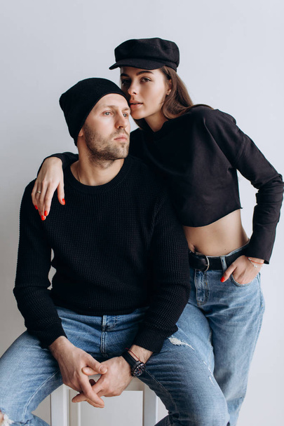 Two hipster models: a man and a woman in a blank black t-shirt, jeans and posing. in a black hat, cap, love, kisses - Foto, immagini