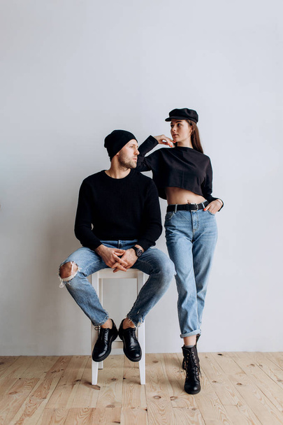 Two hipster models: a man and a woman in a blank black t-shirt, jeans and posing. in a black hat, cap, love, kisses - Photo, image