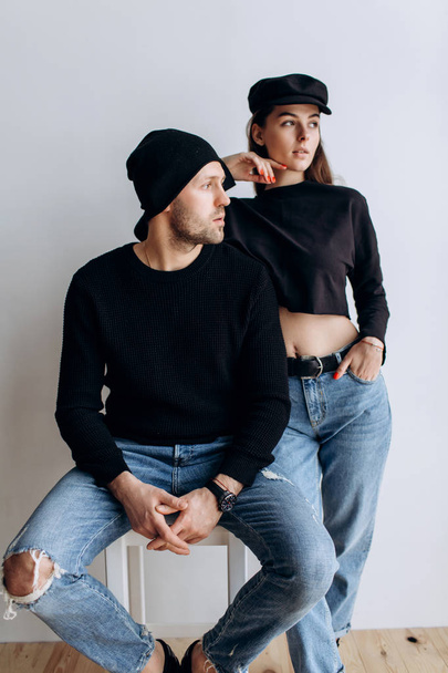 Two hipster models: a man and a woman in a blank black t-shirt, jeans and posing. in a black hat, cap, love, kisses - 写真・画像