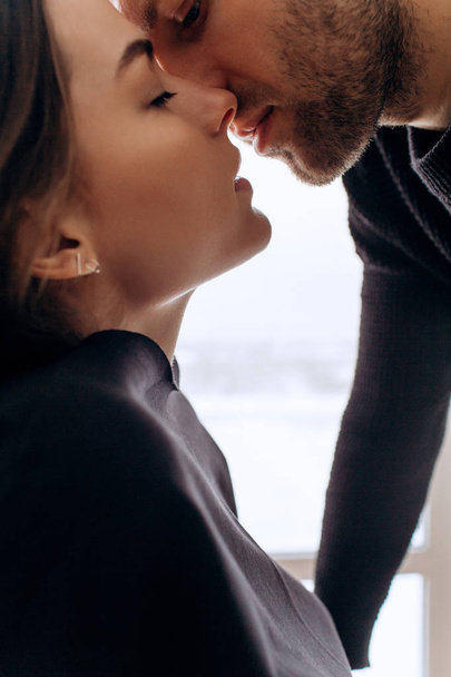 Close-up of young romantic couple is kissing and enjoying the company of each other at home. - Foto, afbeelding