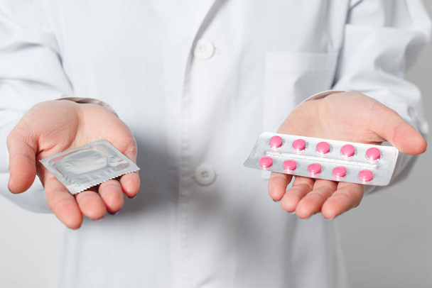 condooms en anticonceptie in de handen van een arts voor veilige sex. - Foto, afbeelding