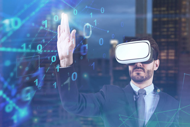 Bearded young businessman in suit and vr goggles standing over night cityscape background and using binary numbers interface. Concept of hi tech. Toned image double exposure - Foto, immagini