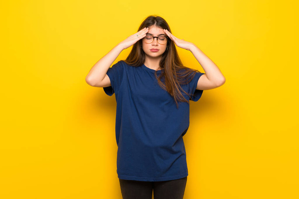 Молода жінка в окулярах над жовтою стіною незадоволена і розчарована чимось
 - Фото, зображення