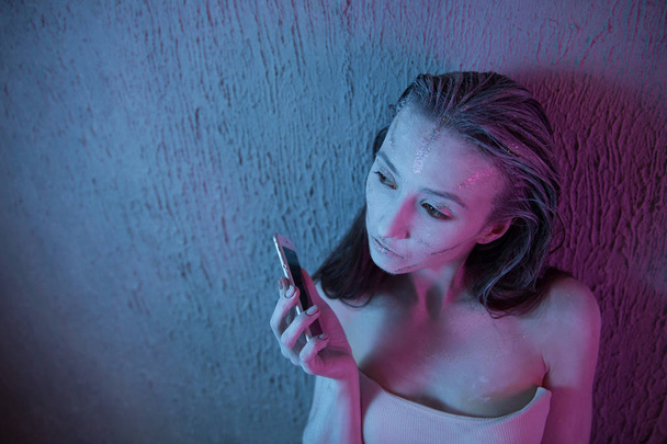 joven adolescente asustada y preocupada sosteniendo el teléfono móvil como víctima acosada en internet abusada y ciberacoso o ciberacoso concepto de estrés en negro
 - Foto, Imagen
