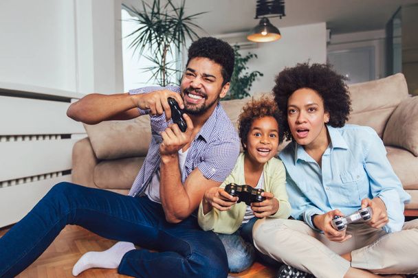 lächelnde Familie, die zusammen auf der Couch sitzt und Videospiele spielt, selektiver Fokus. - Foto, Bild