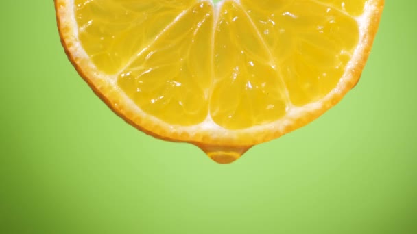 Ρίψη σε μια φέτα πορτοκάλι, φρούτα για δίαιτα και υγιεινή διατροφή. πράσινο backgrond - Πλάνα, βίντεο