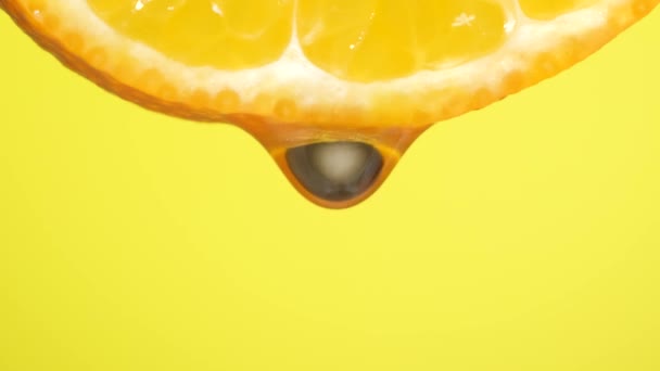 Agua cayendo en una rebanada de naranja, frutas para la dieta y alimentos saludables. Respaldo amarillo
 - Imágenes, Vídeo