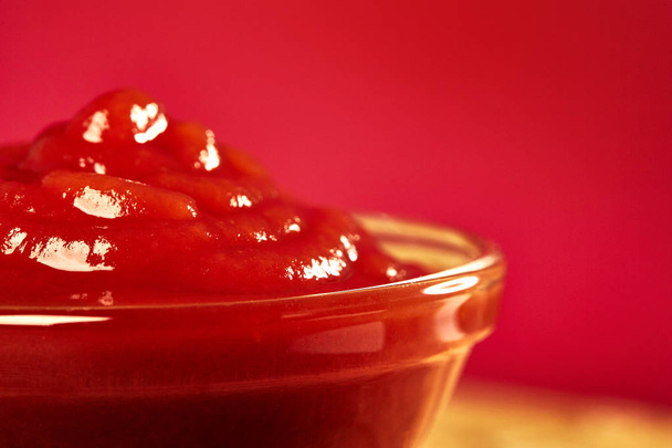 Ketchup in bowl on color background. Portion of tomato sauce.  - Foto, imagen