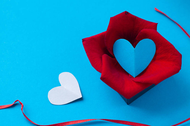 background for Valentine's day and eighth of March, rose petals and heart in box on blue background.the view from the top - Photo, Image