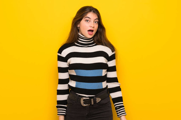 Young woman over yellow wall with surprise and shocked facial expression - Photo, Image