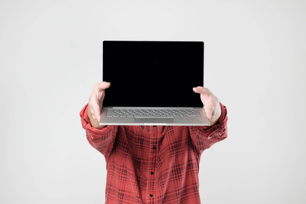 uomo in camicia rossa che trasporta laptop e ne mostra lo schermo in piedi nascondendo il viso
. - Foto, immagini