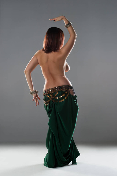 Sexy women performs belly dance in ethnic dress on gray background, studio shot - Foto, imagen