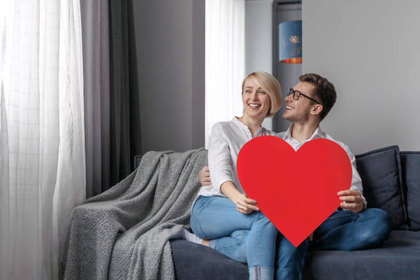 Smiling couple with heart relaxing on couch - Foto, immagini