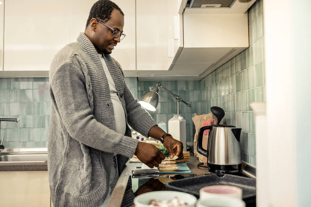 Caring loving husband making morning sandwiches in kitchen - Фото, изображение