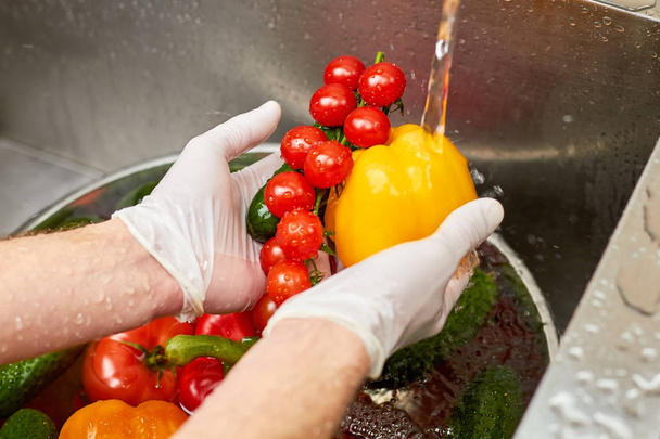 Chef mãos segurando pimentão, caule de tomates cereja e pepino
. - Foto, Imagem