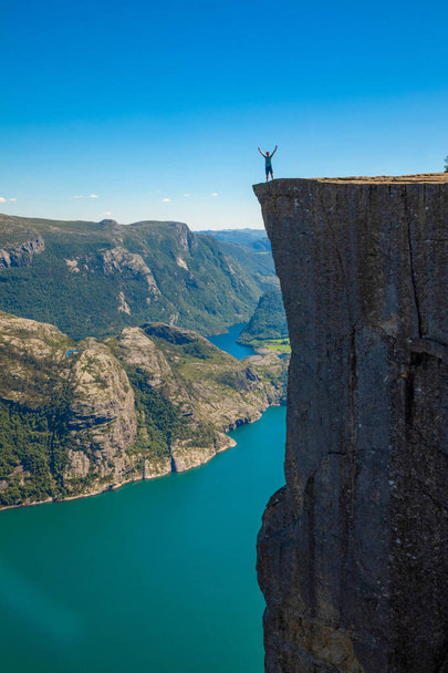 Hiker standing on Preikestolen and looking on the fjerd, Preikestolen - famous cliff at the Norwegian mountains - Φωτογραφία, εικόνα