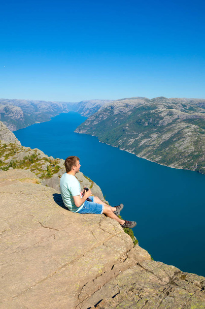 Wanderer steht auf Preikestolen und blickt auf den fjerd, preikestolen - berühmte Klippe im norwegischen Gebirge - Foto, Bild