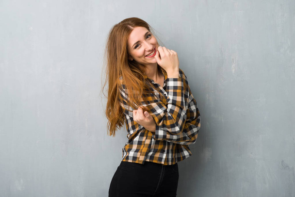 Jonge roodharige meisje over grunge muur glimlachend met een zoete uitdrukking - Foto, afbeelding