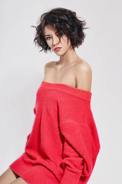 Naked sexy woman with short hair. Girl posing in a red sweater on a white background. Perfect clean skin, sexy Nude body of brunette woman. Skin rejuvenation and hydration - Photo, image