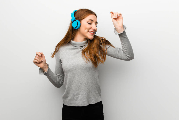 Zrzka dívka nad bílou stěnu poslouchá hudbu se sluchátky a tanec - Fotografie, Obrázek