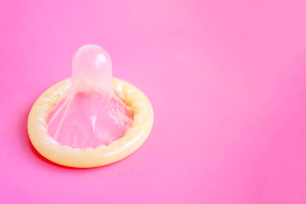 geöffnetes Kondom in Nahaufnahme auf rosa Hintergrund mit Kopierraum - Konzept für kinderfreie und sexuelle Gesundheit. - Foto, Bild
