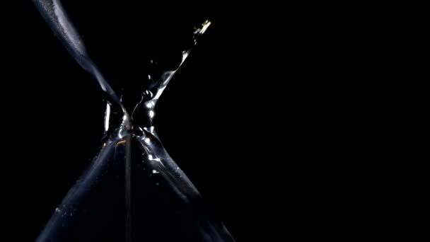 Kum saati siyah arka plan ve yanal kompozisyon ve olası sonsuz döngü yanal ışık arka ışık ile kum akışında - Video, Çekim