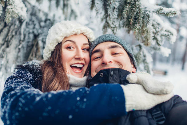 Para zakochanych, biorąc selfie i przytulanie w zimowym lesie. Młodzi ludzie szczęśliwi, zabawy. Koncepcja Walentynki - Zdjęcie, obraz