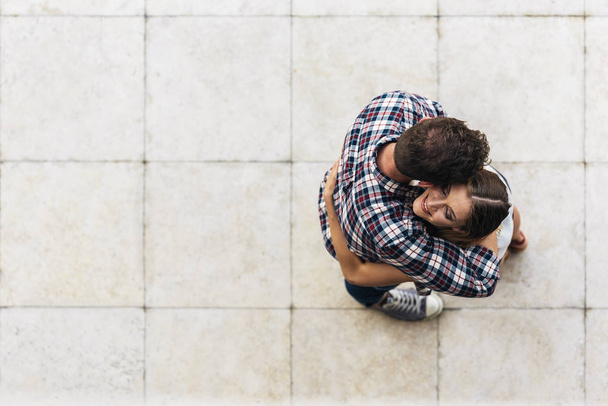 Young loving couple hugging in the street. From top view. Young Love Concept. - 写真・画像