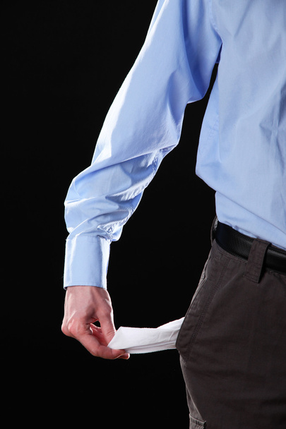 Business man showing his empty pocket, on black background - Foto, imagen