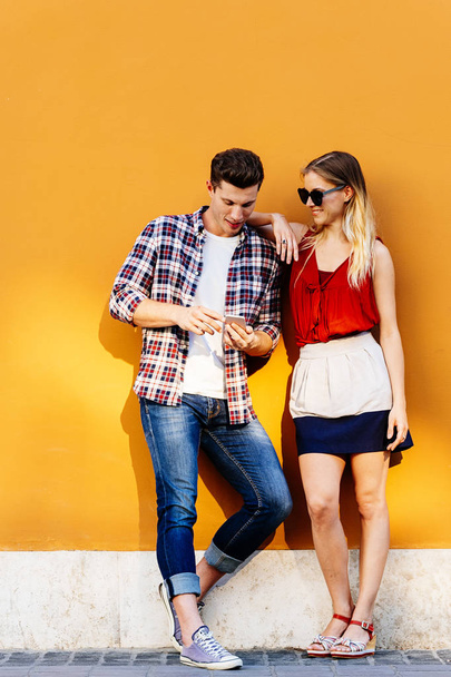 Portrait of young couple using mobile phone in the street. Mobile Concept. - Foto, immagini