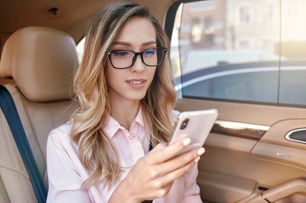 beautiful businesswoman using smartphone in the car - Foto, afbeelding