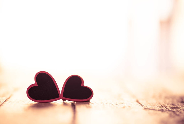 Two red hearts on vintage rustic wooden table and romantic light with background out of focus in Valentines day, love, Mothers Fathers day and Wedding Greeting card concept. Copy space for message. - 写真・画像