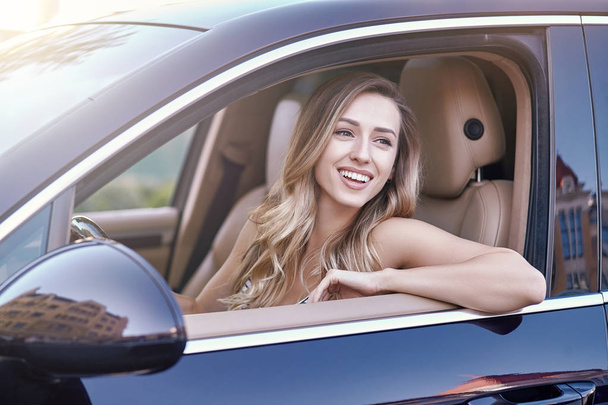 portret atrakcyjne kobiety uśmiechający się siedzi w samochodzie i szukasz drogi - Zdjęcie, obraz